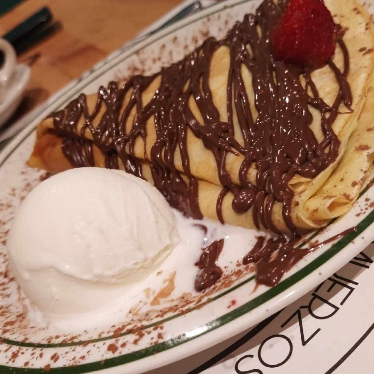 Crepé de frutas con toppings de avellana junto a una porción de helado
