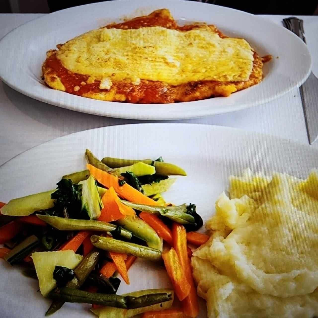 Milanesa a la parmigiana con vegetales salteados y puré de papas 