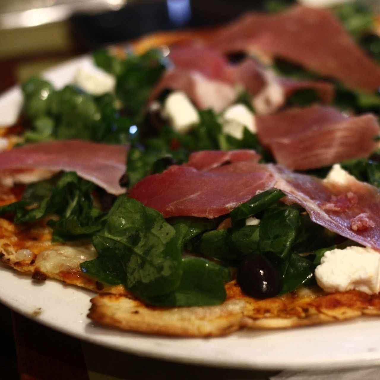 pizza con jamón serrano, queso de cabra y aceitunas negras