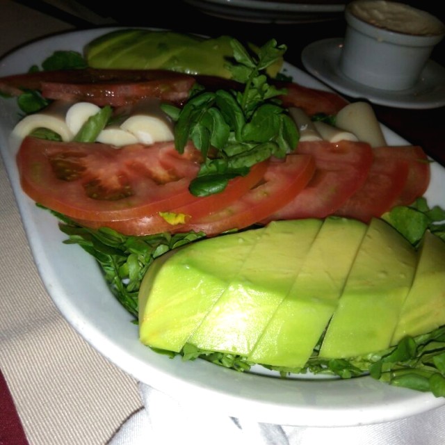 Ensalada de tomate, aguacate y palmito sobre una cama de hojas de berro