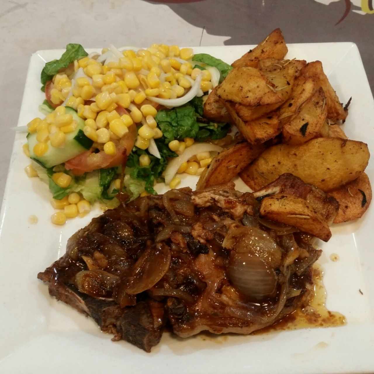 chuleta encebollada acompañada de dos contornos 