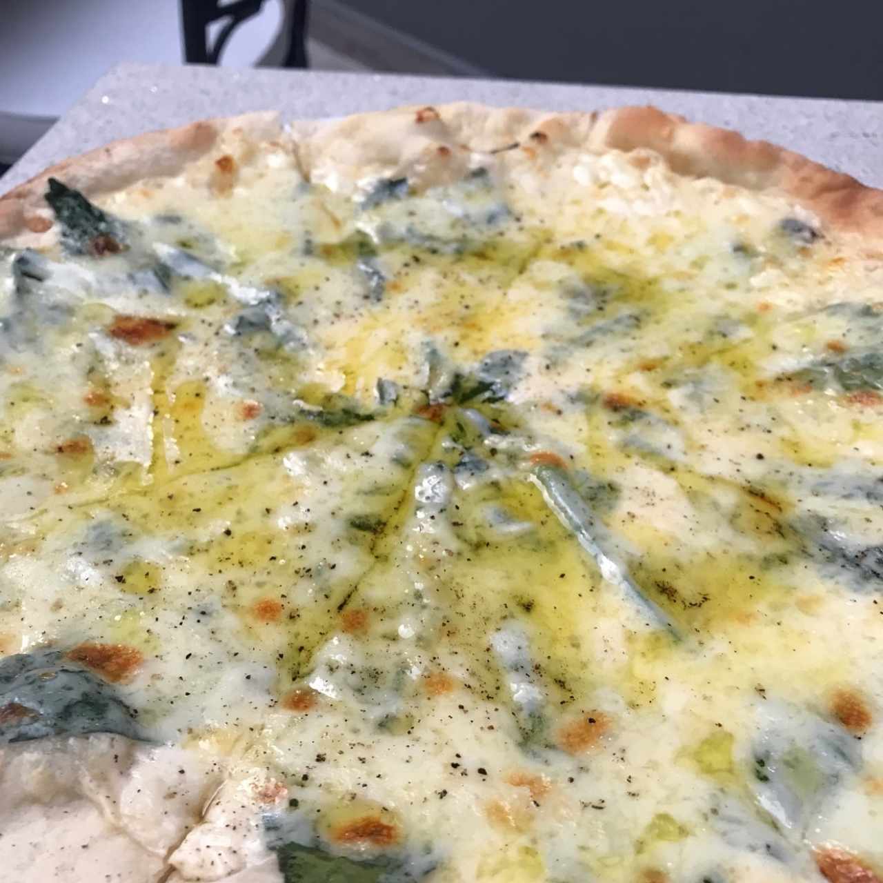 Pizza tres quesos trufada: crema de queso, mozzarella, espinaca, parmesano y aceite de trufa. 