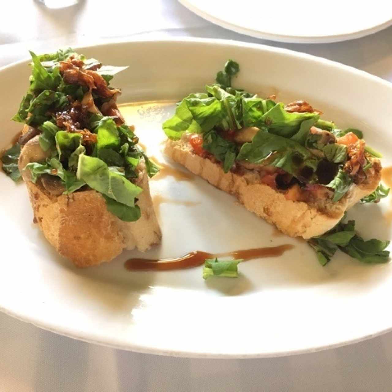 Bruschetas de tomates marinados, cebollas caramelizadas, champiñones y rúgula.