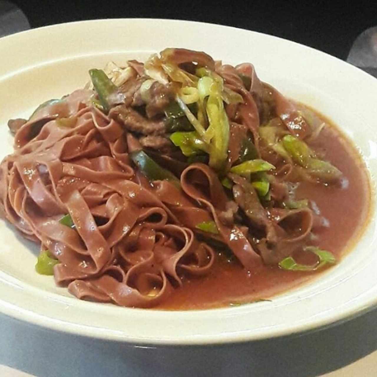 Fetuccini de Tomate Seco, Lomito, Champiñones Frescos, Cebollin y Coulis de Aji dulce
