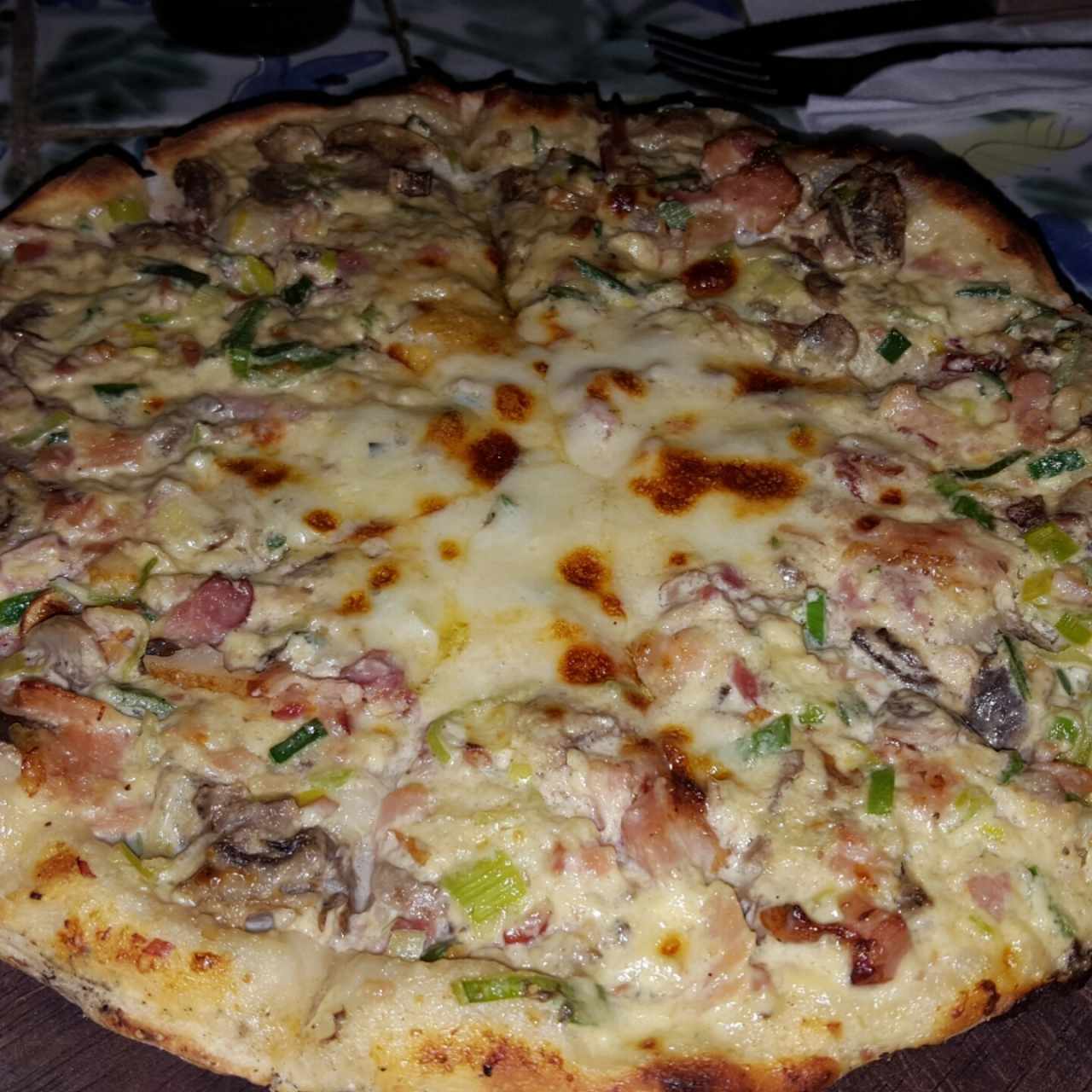 Pizza a base de crema de ajoporro, tocineta y champiñones