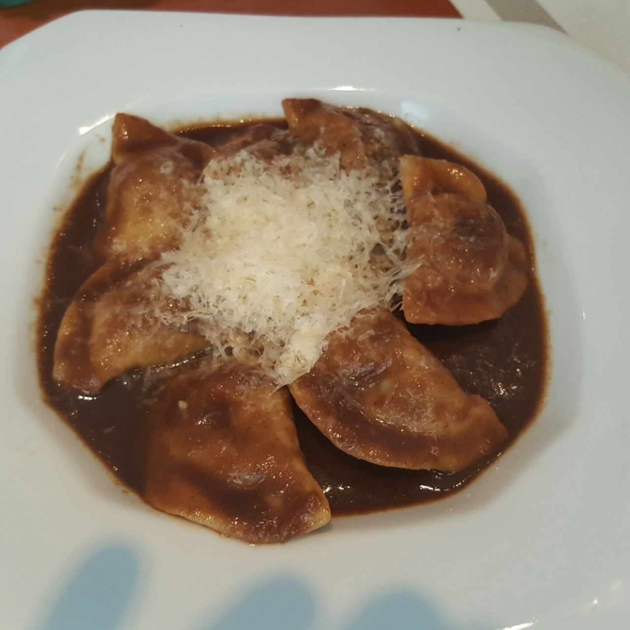 Pasta rellena de asado negro en su salsa con queso parmesano