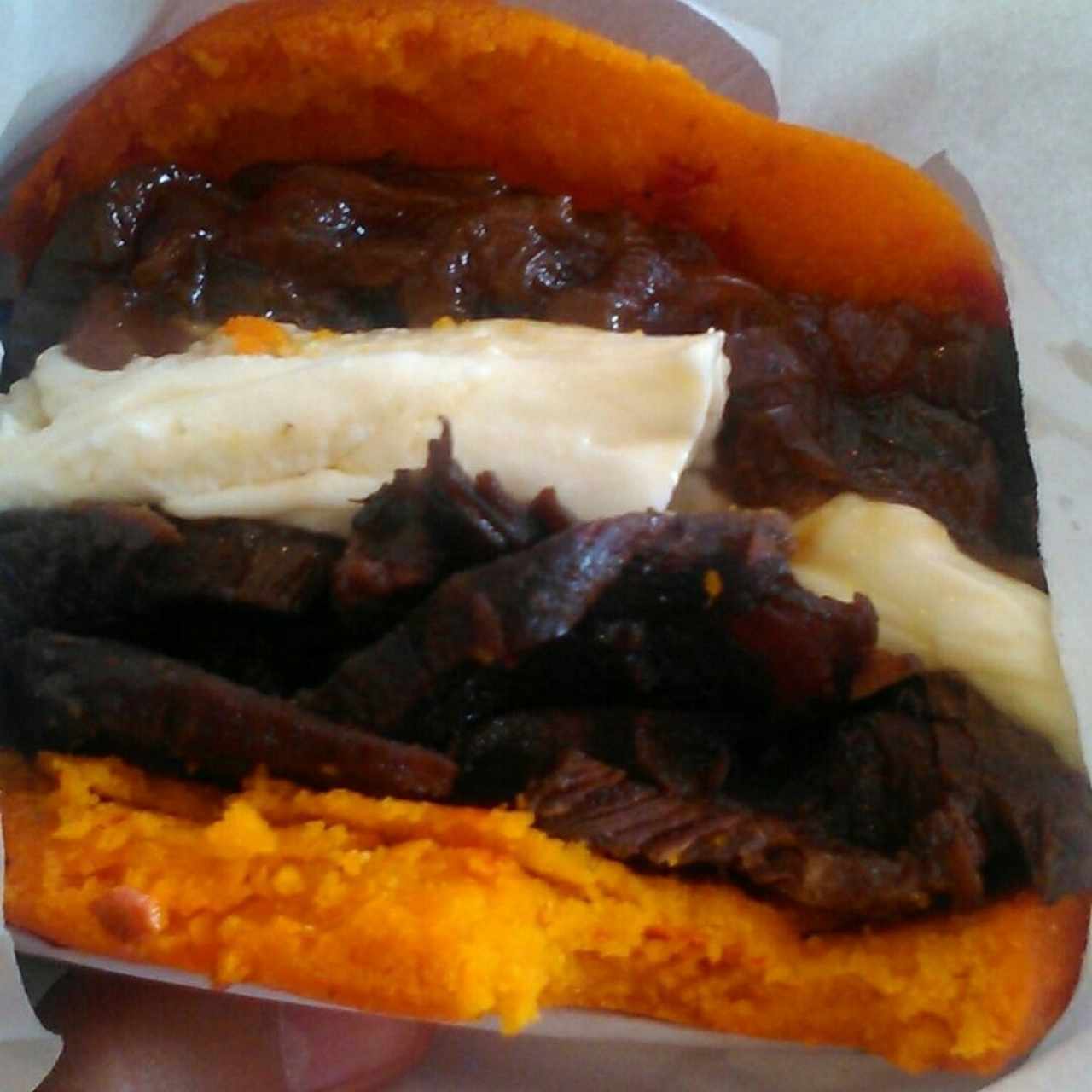arepa de masa de ají rellena de asado negro, cebollas caramelizadas y queso guayanes (te dan vasito con salsa por el asado negro y es divino)