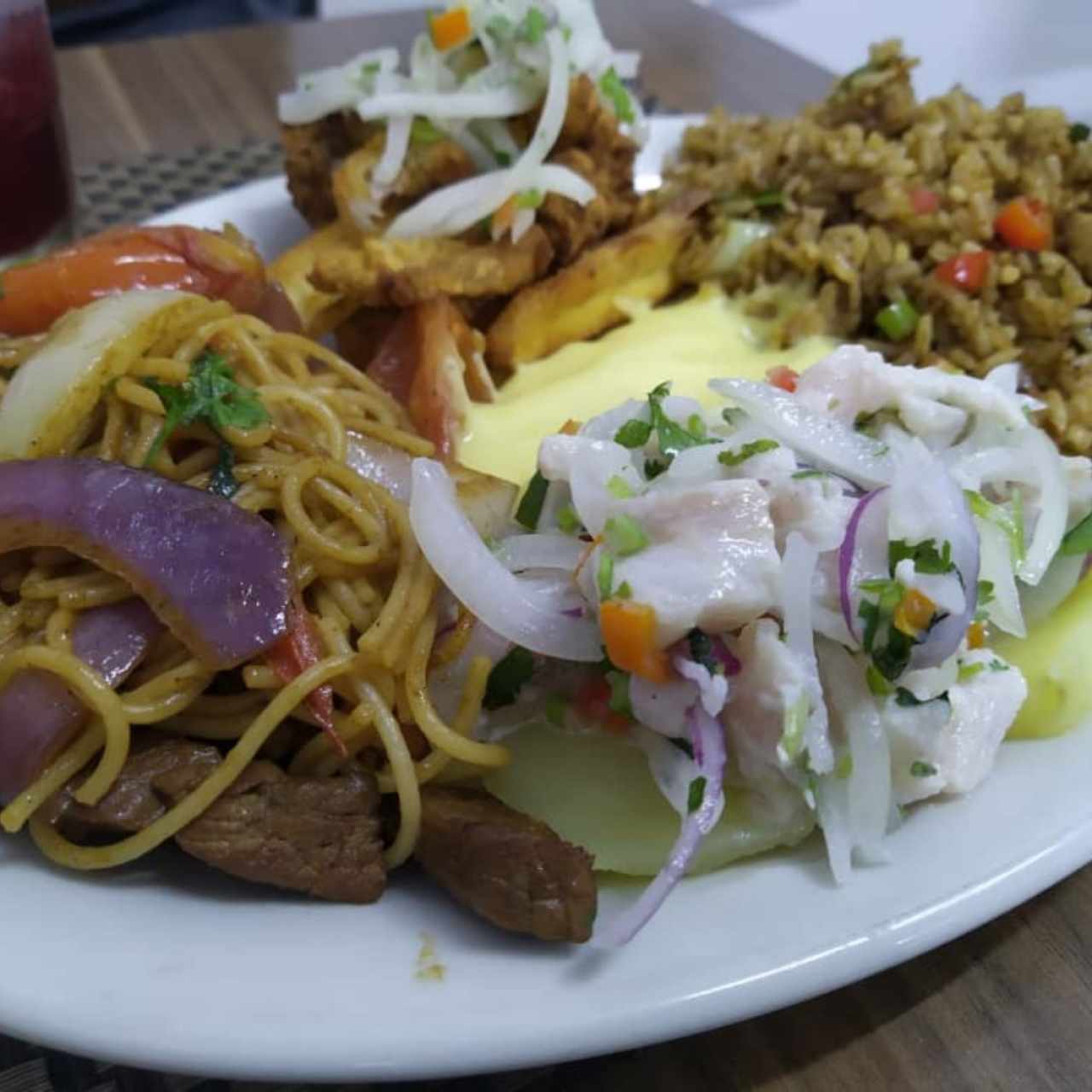 Plato de degustación: Tallarines salteados con carne, papas a la huancaína, ceviche, chicharrón de pescado y arroz chaufa.