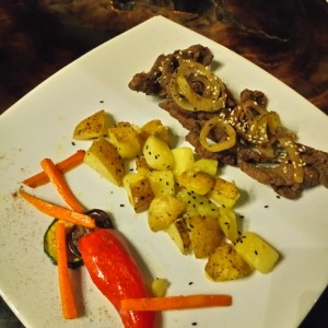 papas asadas con semillas de sésamo, carne asada y vegetales 