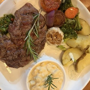 Rib eye con papas salteadas, mac & cheese, ajo y vegetales a la parrilla.