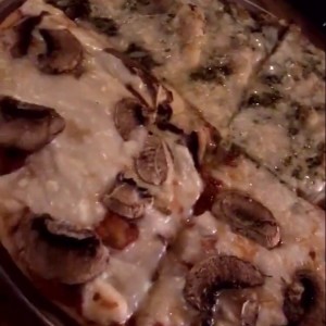 Pizza personal mitad hongos y mitad pesto.