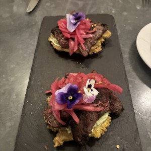 Entrada de carnitas sobre patacones
