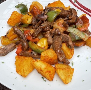 Bistec de Res encebollado sobre papas asadas