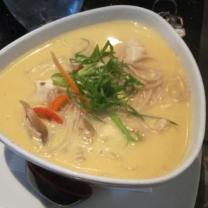 sopa a base de curry y leche de coco con pollo, vegetales y fideos.