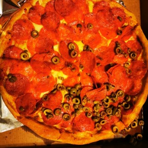 Pizza con doble pepperoni y aceitunas verdes.