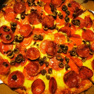 Pizza con doble pepperoni y aceitunas verdes.