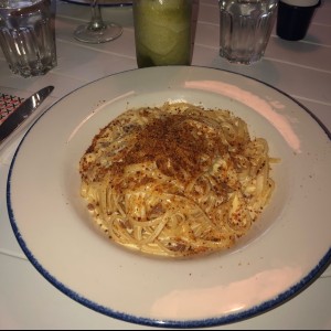 Pasta Larga en salsa alfredo con prosciutto y migas de Pana