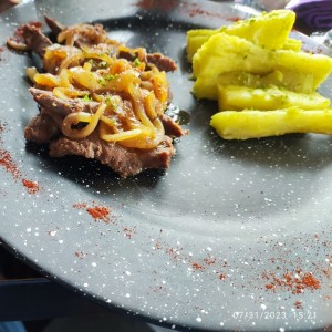 Bistec encebollado con yuca al mojo.