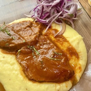 Carne en cama de pure y cebollas
