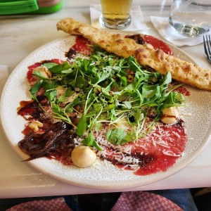Entradas - Carpaccio de Res con Arrugula y cebolla caramelizada