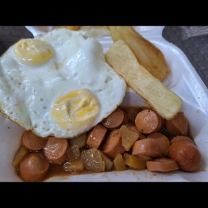 par de huevos fritos con salchicha guisada y yucas fritas.