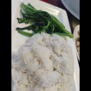 Gallina de patio con arroz blanco y hojas de mostaza