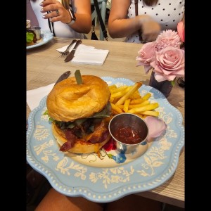 Burger con queso cheddar, cebollas caramelizadas, tomate y papas fritas