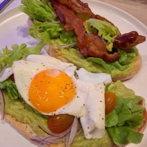 Avocado toast especial con aguacate, huevo frito, bacon dorado, lechuga y tomate cherry