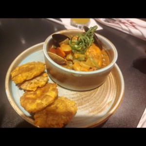 Estofado de mariscos salteados con vegetales frescos en salsa criolla, acompañado de crujientes patacones