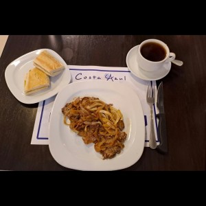 Bistec encebollado con pan tostado.