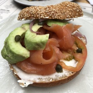 Bagel con salmón ahumado, aguacate, queso crema y alcaparras 
