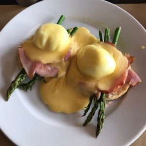 huevos benedictinos sobre cama de esparragos y arepa de maiz pilado