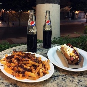 Papas con queso cheddar y tocineta. Perro caliente