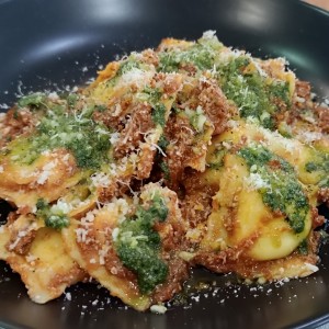 raviolis rellenos de ricotta y ajoporro, con salsa boloña y pesto de albahaca 
