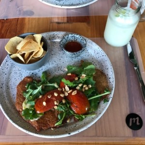 Milanesa en queso brie, miel, nueces y rugula con tomates
