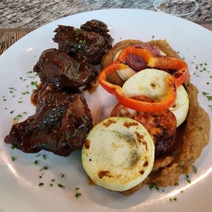 Asado negro de cordero, con vegetales al fierro, en cama de puré de plátano 