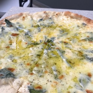 Pizza tres quesos trufada: crema de queso, mozzarella, espinaca, parmesano y aceite de trufa. 