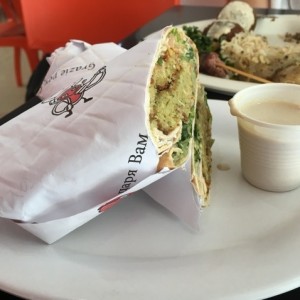 sandwich de falafel y al fondo plato mixto