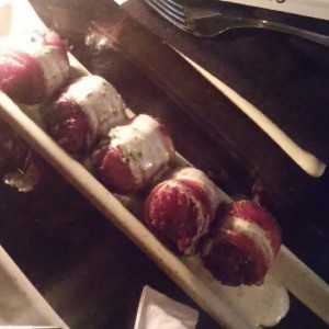 Datiles y chorizo envueltos en tocineta con salsa de yogurt
